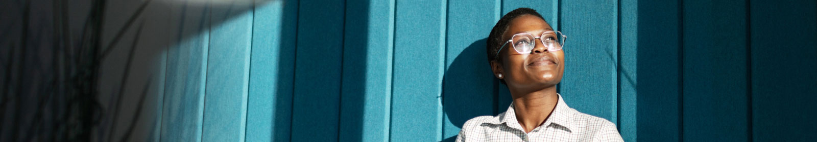 A person standing in front of a colorful blue wall and looking off into the distance