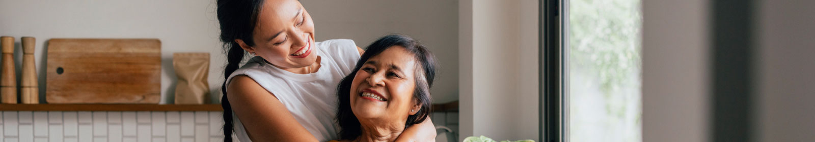 adult daughter embracing her mother in a kitchen