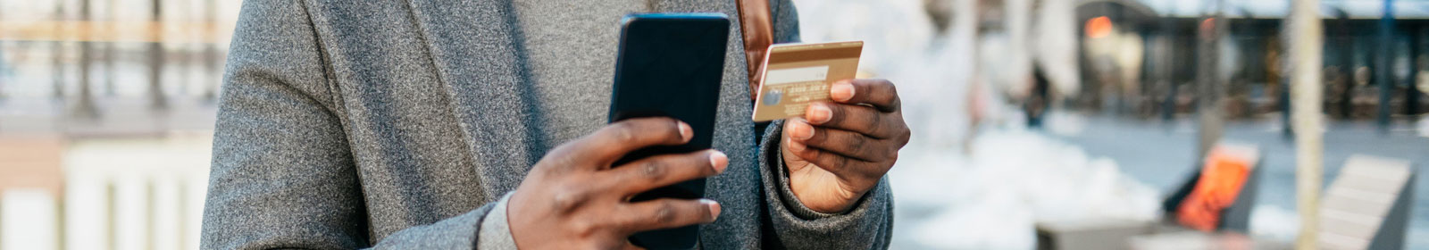 a close-up of a person's hands holding a smartphone and a credit card
